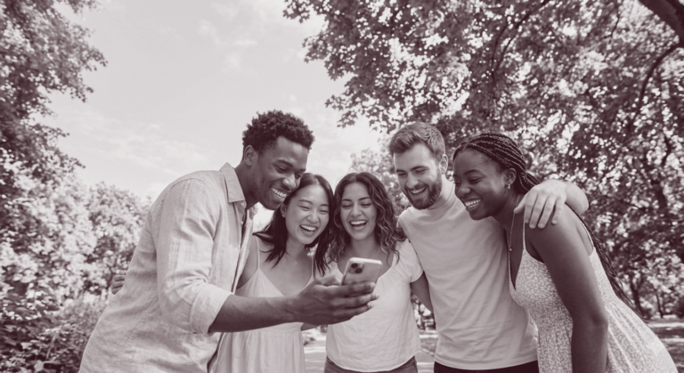Social Media Management Freelancer: fünf Freunde liegen sich in den Armen und schauen auf ein Handy, Community Building